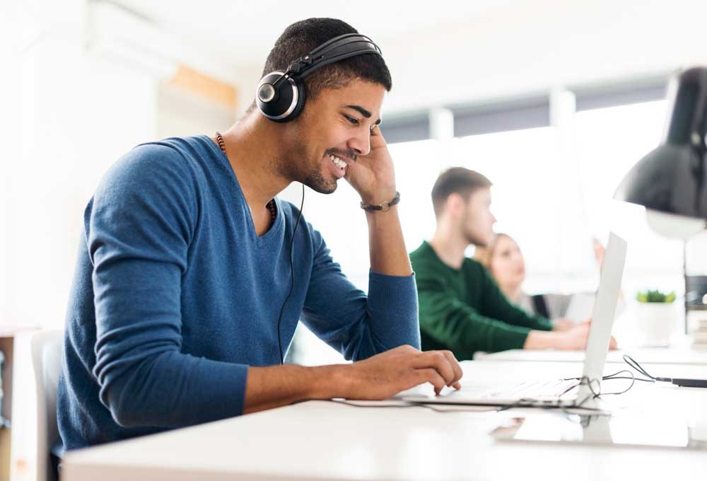 A man talking on a phone while using a laptop