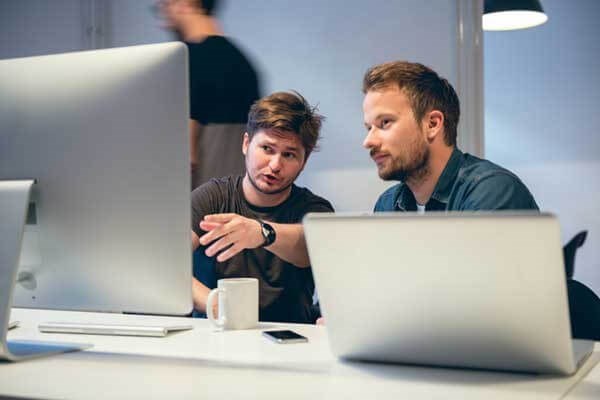 Two colleagues chatting at a computer about work